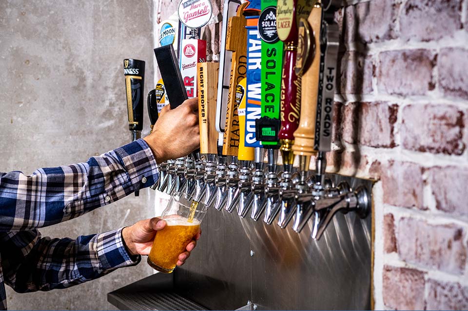 A person pouring their own beer from a number of beers on tap