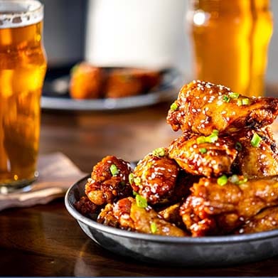 Buffalo wings topped with sesame seeds and chives. Served with beer.